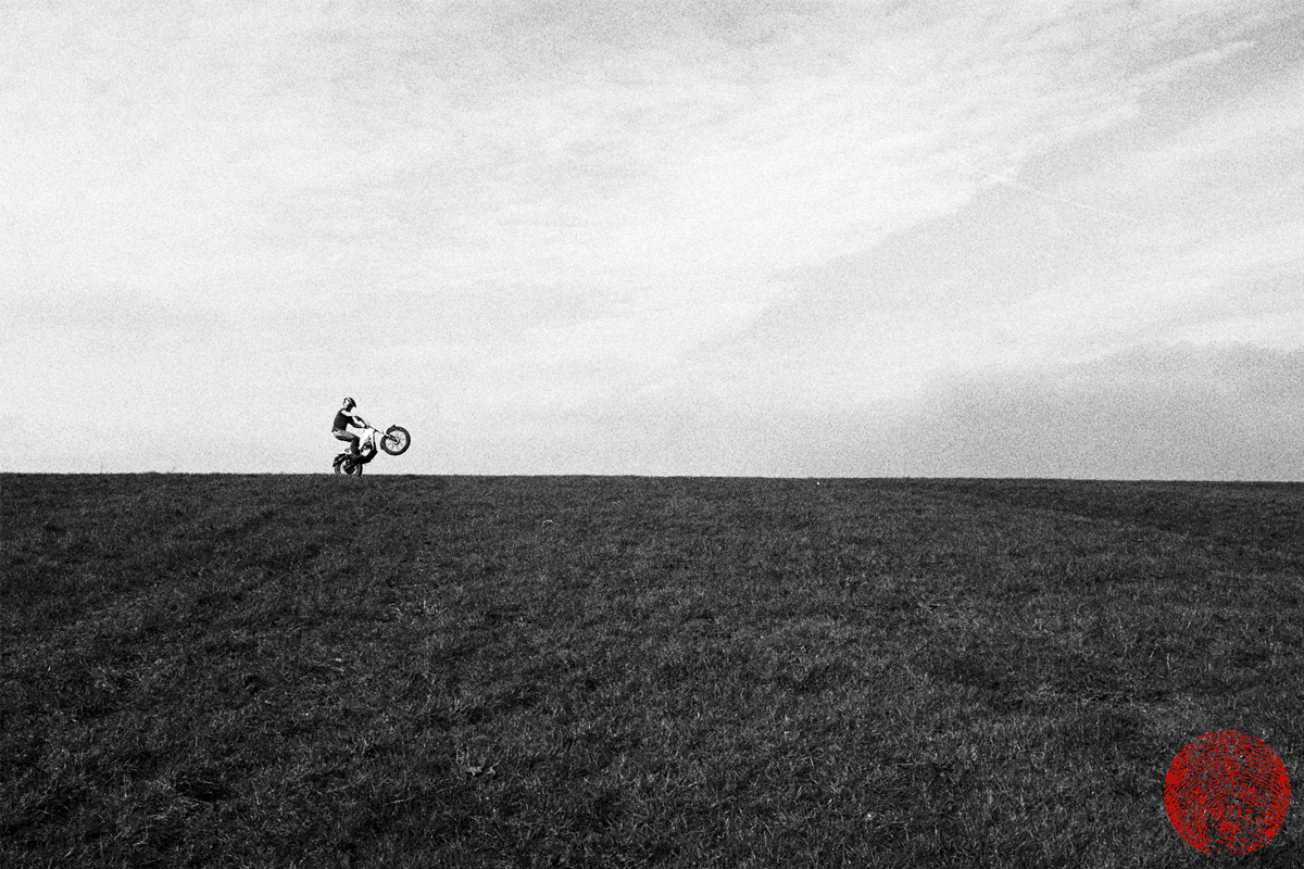 motorcyclist doing a wheelie along a ridge on a vintage yamaha ty175